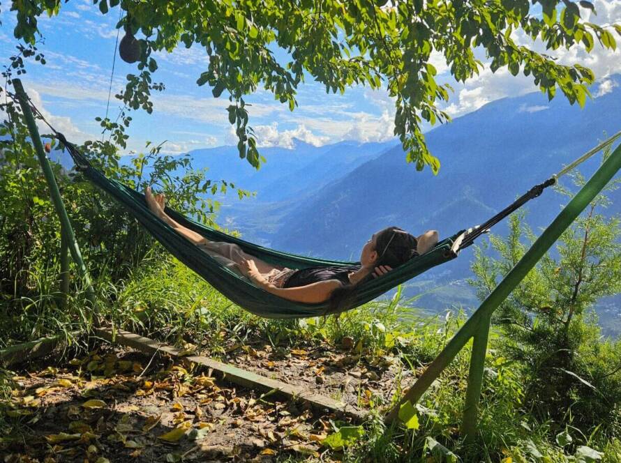 Solo female traveler relaxing in a hammock with Himalayan mountain views at GlampEco Manali